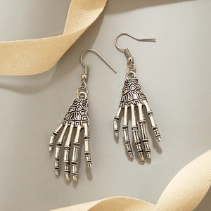 Vintage silver skeleton hand earrings in gothic style on light grey background