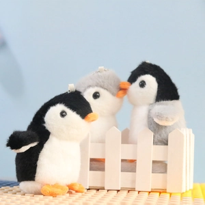 Three small plush penguin keychains in black and grey, featuring soft fur textures