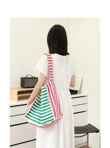 Vista posteriore di una modella con borsa tote in maglia a righe verdi rosa e bianche