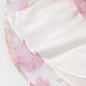 Detailed close-up showing the layered pink floral hem with white satin lining and mesh