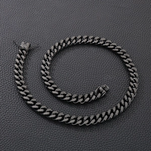 Macro shot of black stainless steel Cuban chain on dark leather texture surface