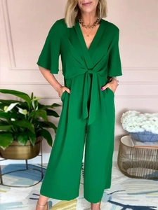 Detail of green V-neck jumpsuit featuring wide leg trousers and elegant waist tie knot