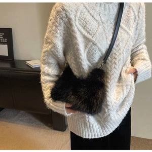 Detail of black faux fur plush crossbody bag with slim strap and metal hardware