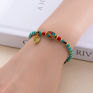 Bracelet ethnique à perles avec pendentif feuille sur poignet montrant les détails