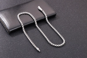 Macro shot of silver stainless steel box chain with industrial lobster clasp on leather