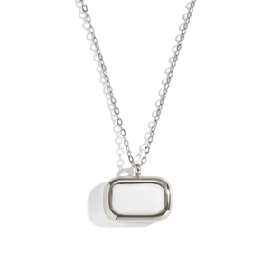 Détail d'un pendentif rectangulaire en argent avec design ajouré sur fond blanc épuré