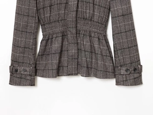 Détail de veste à carreaux gris avec ourlet volanté et poignets ceinturés à boutons