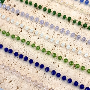 Macro shot of 3-4mm colorful faceted crystal bead chains on minimalist stone base