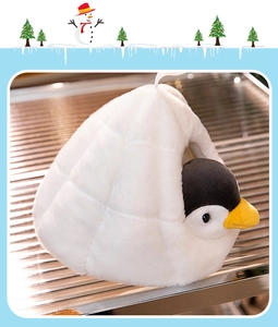 Close-up of cute plush penguin nesting in a soft white fabric igloo winter scene