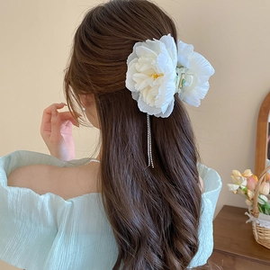 Detail of elegant white fabric flower hair claw clip with sparkling rhinestone tassels