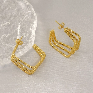 Three-layer twisted gold stud earrings in stainless steel on a textured grey background