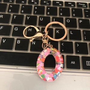 Detail view of zero-shaped resin keychain with colorful heart sequins on laptop keyboard