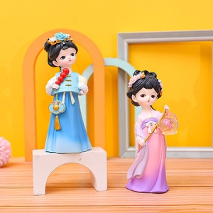 Detailed view of two cute ancient style dolls in blue and purple outfits on a wooden stand
