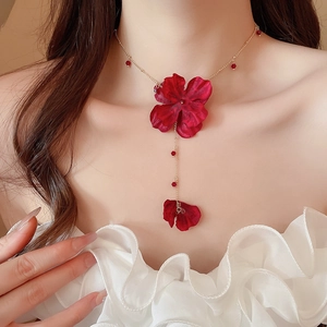Close-up of red fabric flower pendant necklace with gold chain on model's neckline