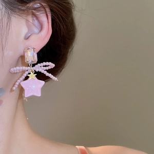 Close-up of pink crystal bow and star pendant necklace on a woman's neckline