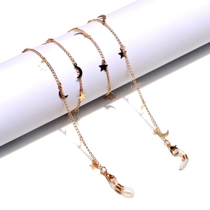 Handmade gold eyewear chain with celestial star and moon charms on a minimal pedestal