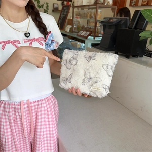 Detail of white plush lace butterfly cosmetic bag with soft faux fur texture and brand label