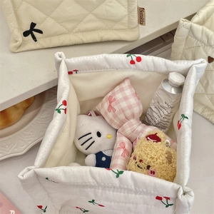 Detalle de la cesta de almacenamiento acolchada blanca con estampado de cerezas y objetos