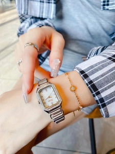 Detail of square mother-of-pearl watch with crystal bezel and matching gold jewelry