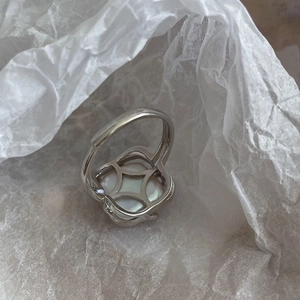 Detail view of 925 sterling silver ring with white clover shell inlay on wrinkled paper