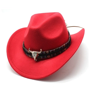 Détail d'un chapeau de cowboy en feutre rouge avec bande ethnique et pendentif crâne de taureau