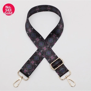 Detail of adjustable geometric strap with pink and green patterns and gold metal hooks
