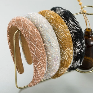 Close-up of padded headbands featuring dense rhinestones on a decorative metal stand
