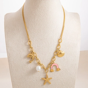Detail of golden charm necklace with sea-themed pendants including pearls and dolphins