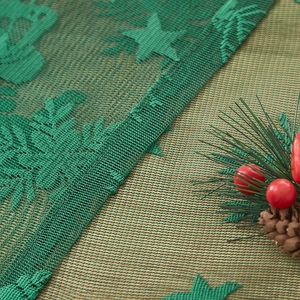 Detail der grünen Weihnachts-Tischdecke mit Sternen- und Glocken-Jacquard-Muster