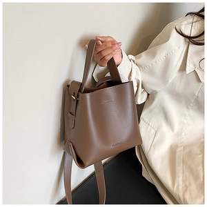 Detailed view of dark brown leather bucket bag featuring handles and embossed logo