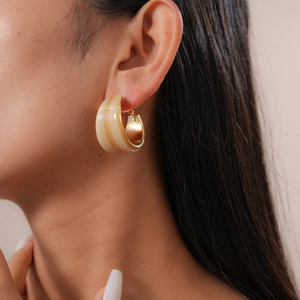 Close-up of geometric resin C-shape hoop earrings with gold metal trim on model