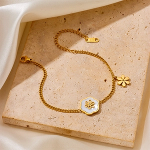 Detailed view of a gold Cuban chain bracelet featuring shell flower charms on stone