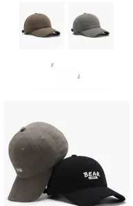 Detail of embroidered BEAR letters on cotton baseball caps in khaki, gray and black colors