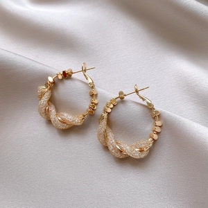 Detail of gold twisted mesh hoop earrings featuring metallic sequins on champagne satin