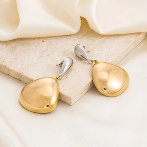 Two-tone gold and silver teardrop earrings on travertine stone with silk fabric