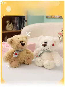 Detalle de osos de peluche marrón y blanco con bufandas grises y bordado de corazón rojo