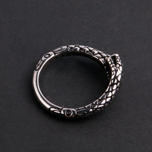Detailed macro view of silver stainless steel ring with snake scale texture on dark background
