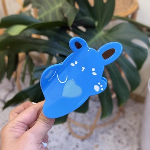 Detailed view of a cute blue acetate rabbit hair claw clip held in hand with soft focus