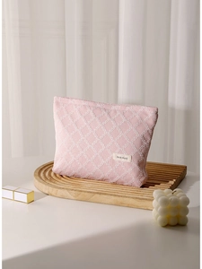 Beauty case rosa trapuntato con motivo 3D ed etichetta tessuta su vassoio in legno