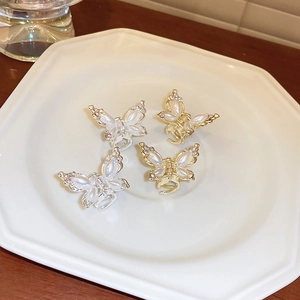 Macro detail of mini butterfly hair claws with pearls and rhinestones on a ceramic plate