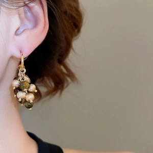 Macro shot of gold hoop earrings with brown faceted beads and matte gold spheres
