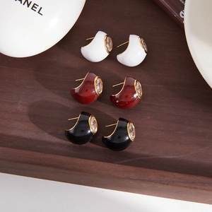 Detail of vintage enamel earrings set with zircon stones on a rustic wooden display tray