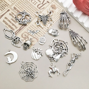 Flat lay of vintage silver gothic Halloween charms including skulls and spiders on paper