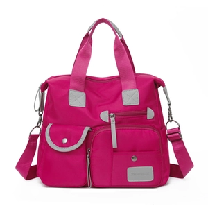 Detail of fuchsia nylon tote bag showing multiple pockets and adjustable shoulder strap