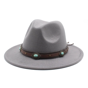 Détail de la bande en cuir marron avec clous turquoise sur un chapeau en laine
