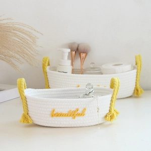 Close-up of white woven cotton storage baskets with yellow tassels and beautiful embroidery