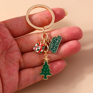 Detailed close-up of golden Christmas keychain with green tree and gift box charms