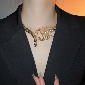 Close-up of golden scorpion choker necklace with rhinestones worn on neck with black blazer