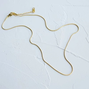 Detailed close-up of golden stainless steel snake chain necklace with lobster clasp