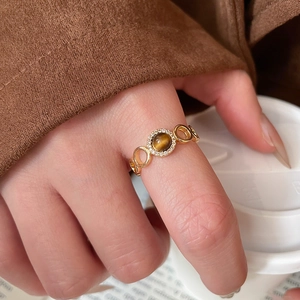 Close-up of gold plated tiger eye ring with diamonds worn against a cozy background